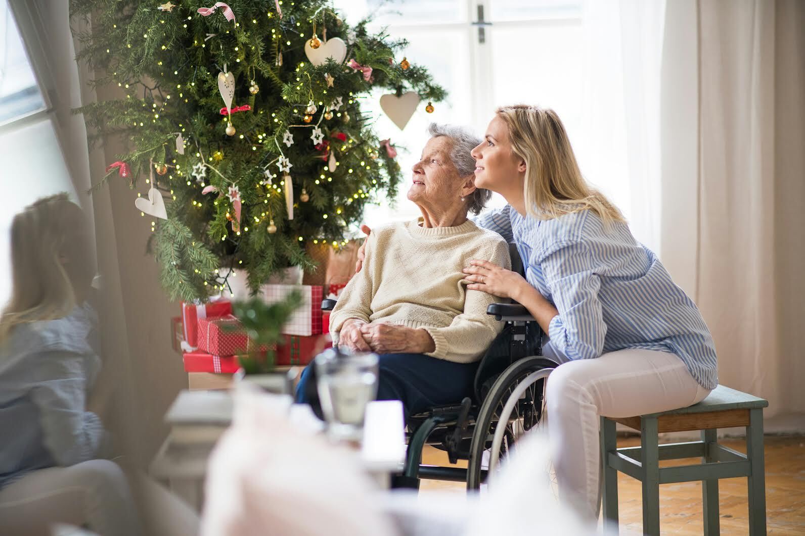 woman and elderly woman sitting by a christmas tree